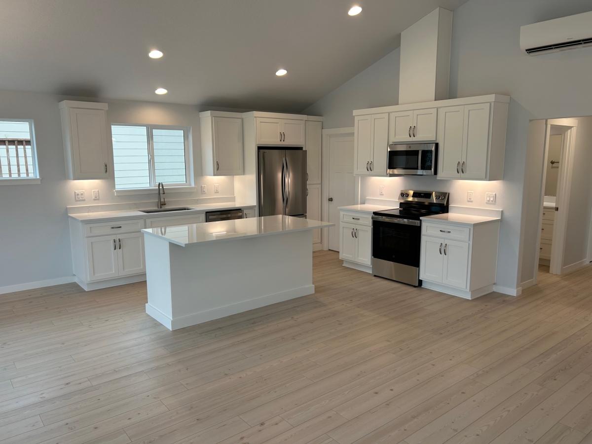 Finished white kitchen with island, quartz counters, and stainless appliances